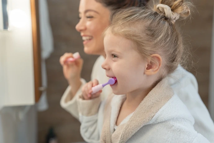 Enfant qui se lave les dents avec sa maman